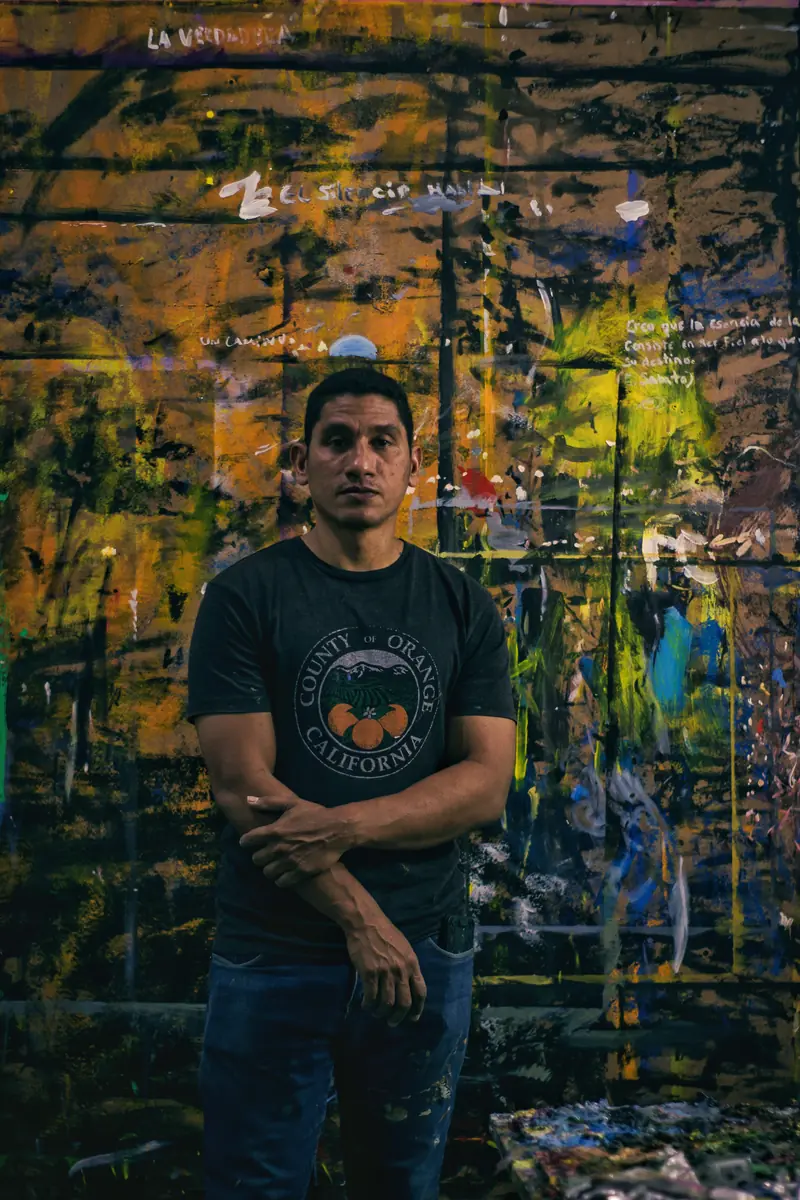 Johan Galué in his studio, standing before one of his golden-wall paintings